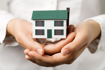 A pair of hands holding a small house. Real estate or insurance concept.